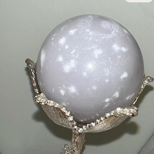 Gray and white polished crystal sphere in a silver stand