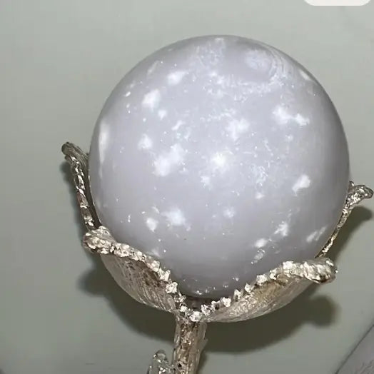 Gray and white polished crystal sphere in a silver stand