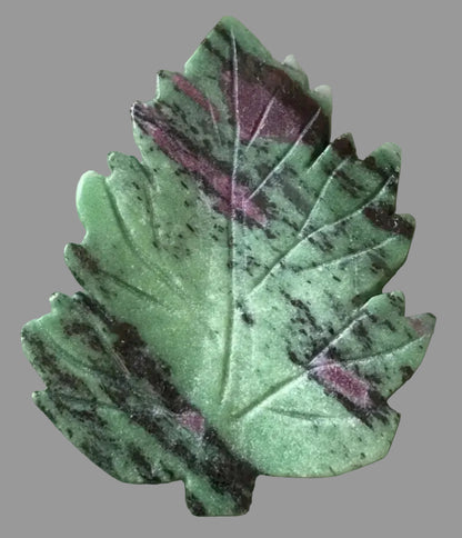 close up leaf carved from ruby zoisite crystal.  bright green, black and pink throughout