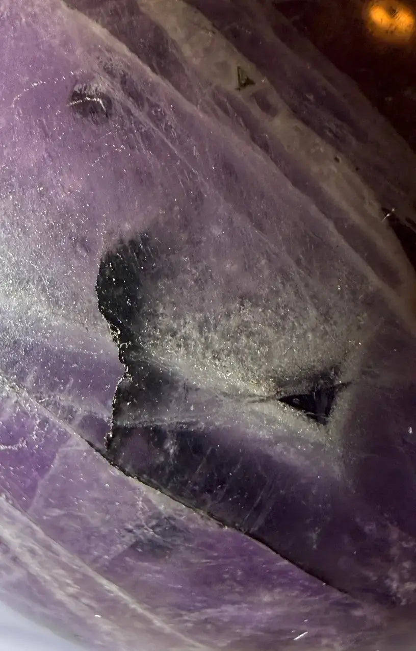 magnified close up surface of amethyst sphere - druzy pocket filled with clear quartz crystals and the iron rich plate inclusion