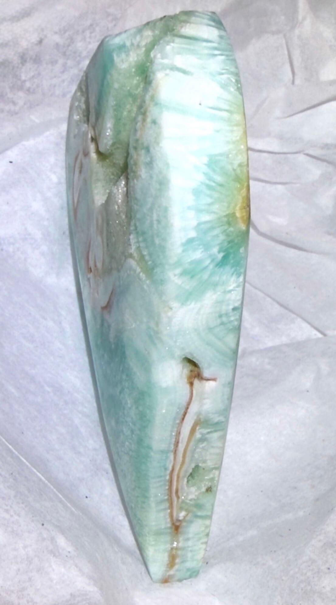 nice close up side view photo of a caribbean calcaite freeform showing the soft bues and greens with banding and the creamy browns of the aragonite