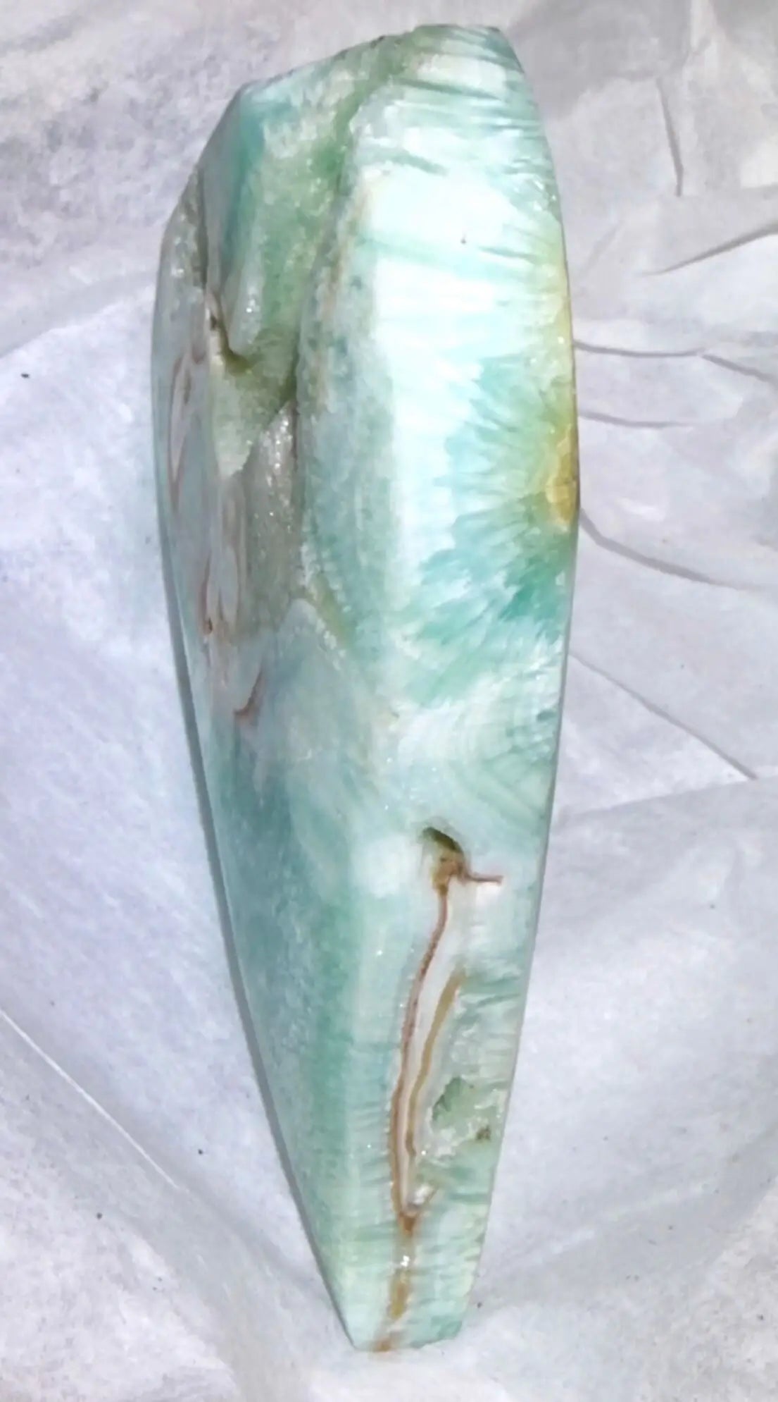 nice close up side view photo of a caribbean calcaite freeform showing the soft bues and greens with banding and the creamy browns of the aragonite