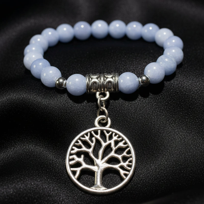 A close-up of a beaded necklace featuring Angelite round beads, silver spacer beads, and a dangling  tree of life charm in silver-tone metal 