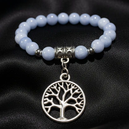 A close-up of a beaded necklace featuring Angelite round beads, silver spacer beads, and a dangling  tree of life charm in silver-tone metal 
