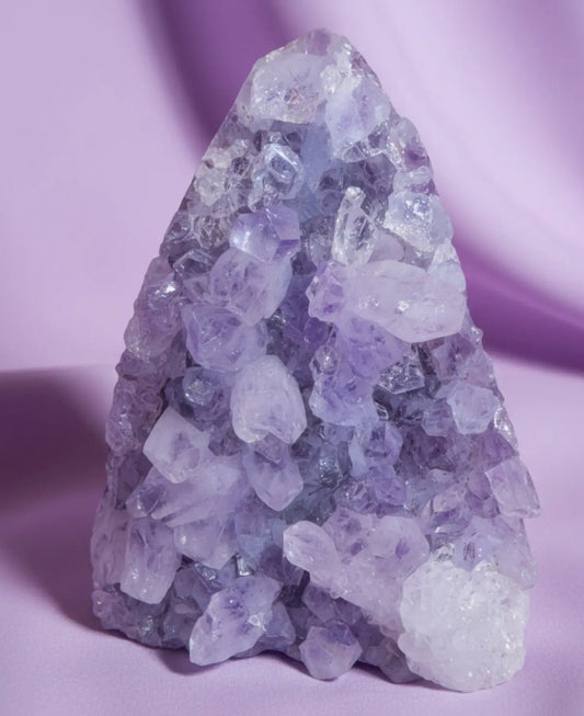close up of an amethyst geode with a lavender fabric behind 