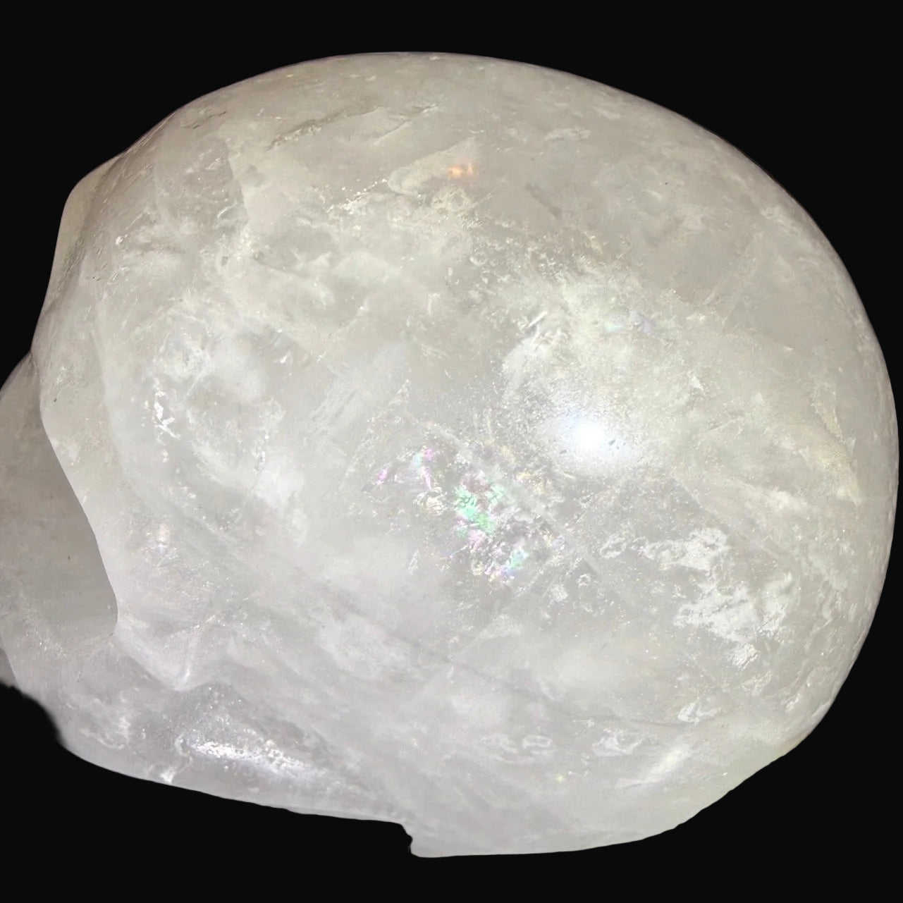close up clear quartz hand carved skull with multiple rainbows 