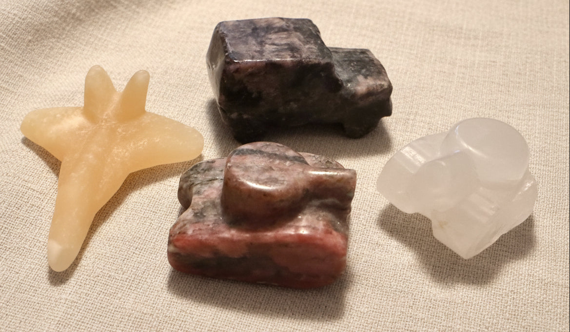 photo of four hand carved pieces, two tanks, clear quartz with citrine inclusion, brecciated jasper, yellow calcite jet, and yooperlite jeep truck  
