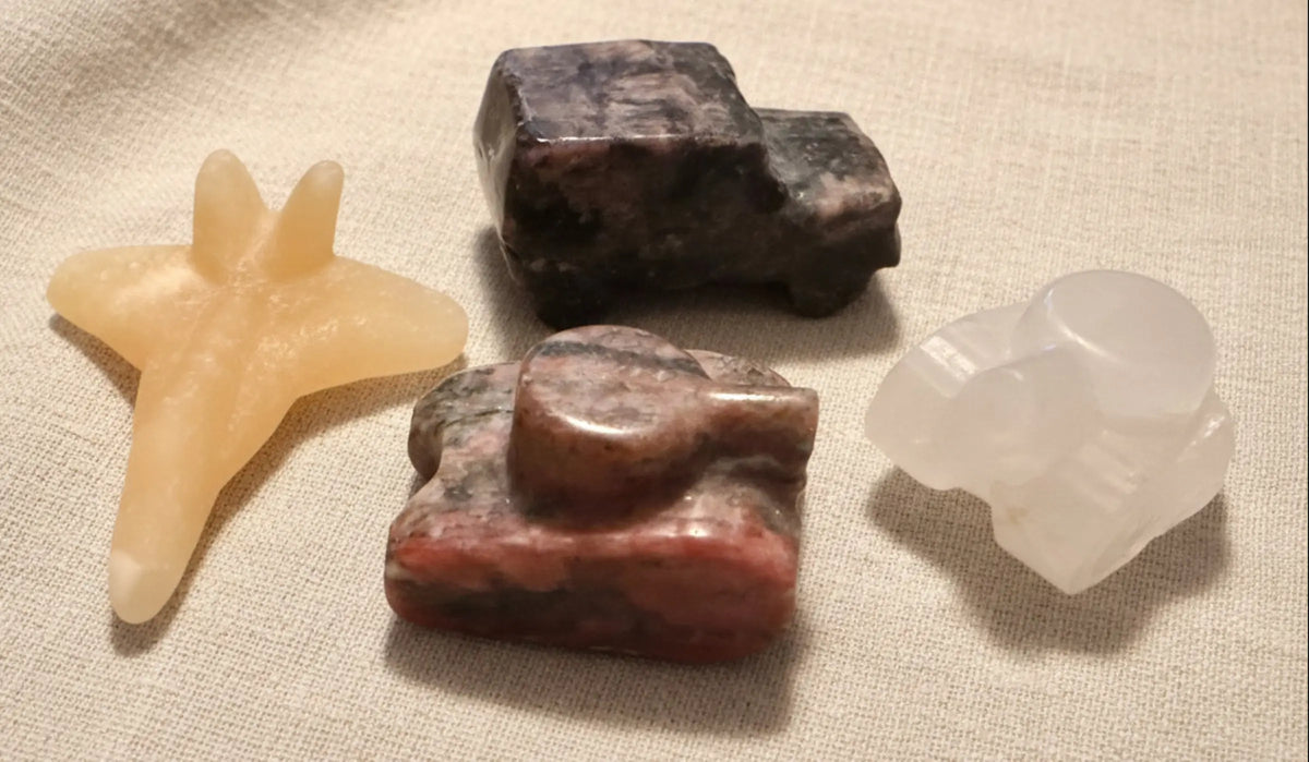 photo of four hand carved pieces, two tanks, clear quartz with citrine inclusion, brecciated jasper, yellow calcite jet, and yooperlite jeep truck  