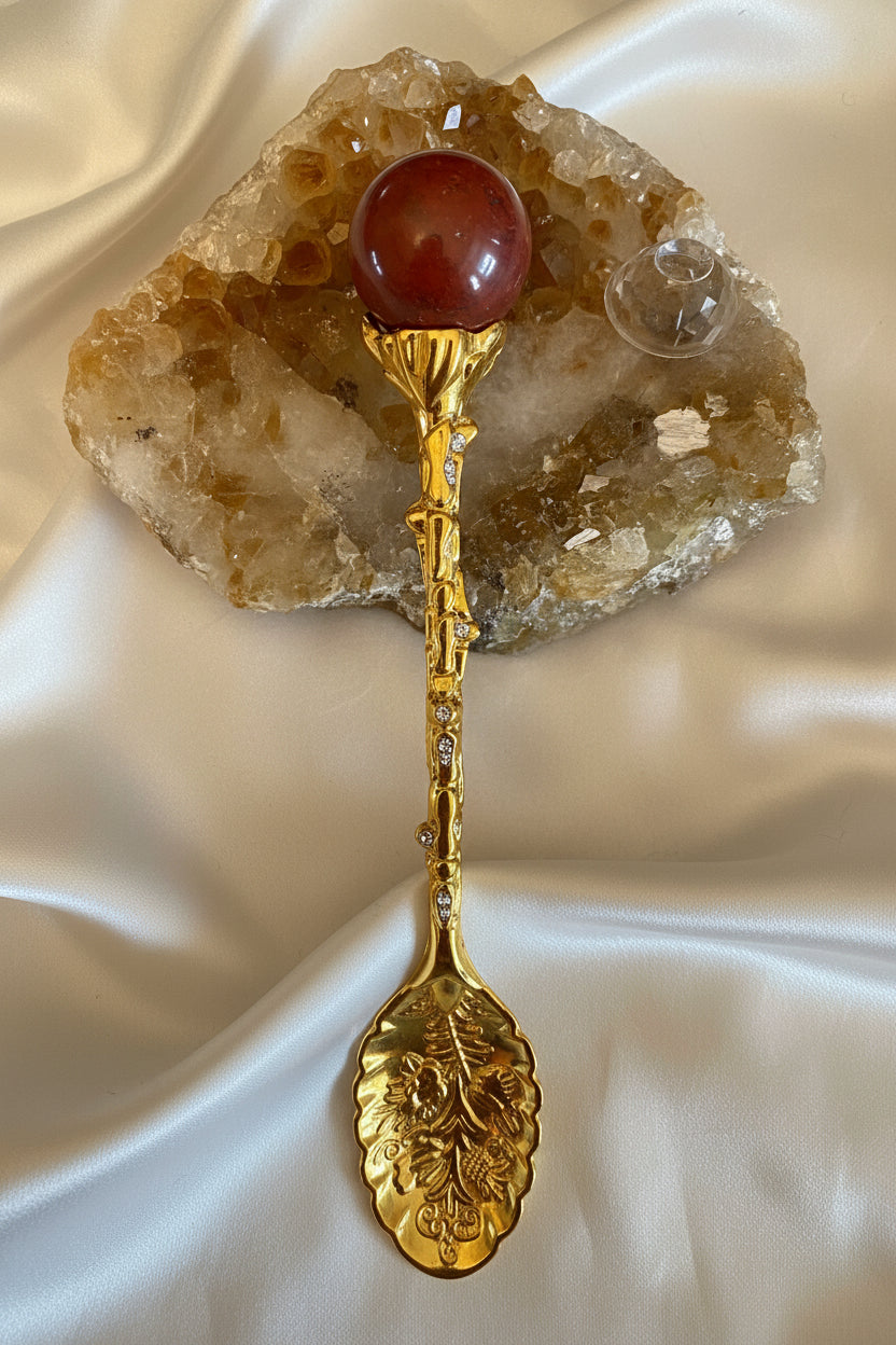 close up of gold tone carved spoon with crystal topper on a slab 