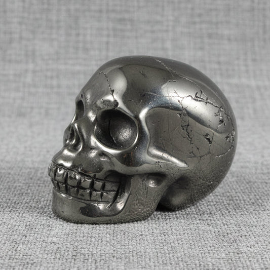 side view of silvery color polished carved hematite skull