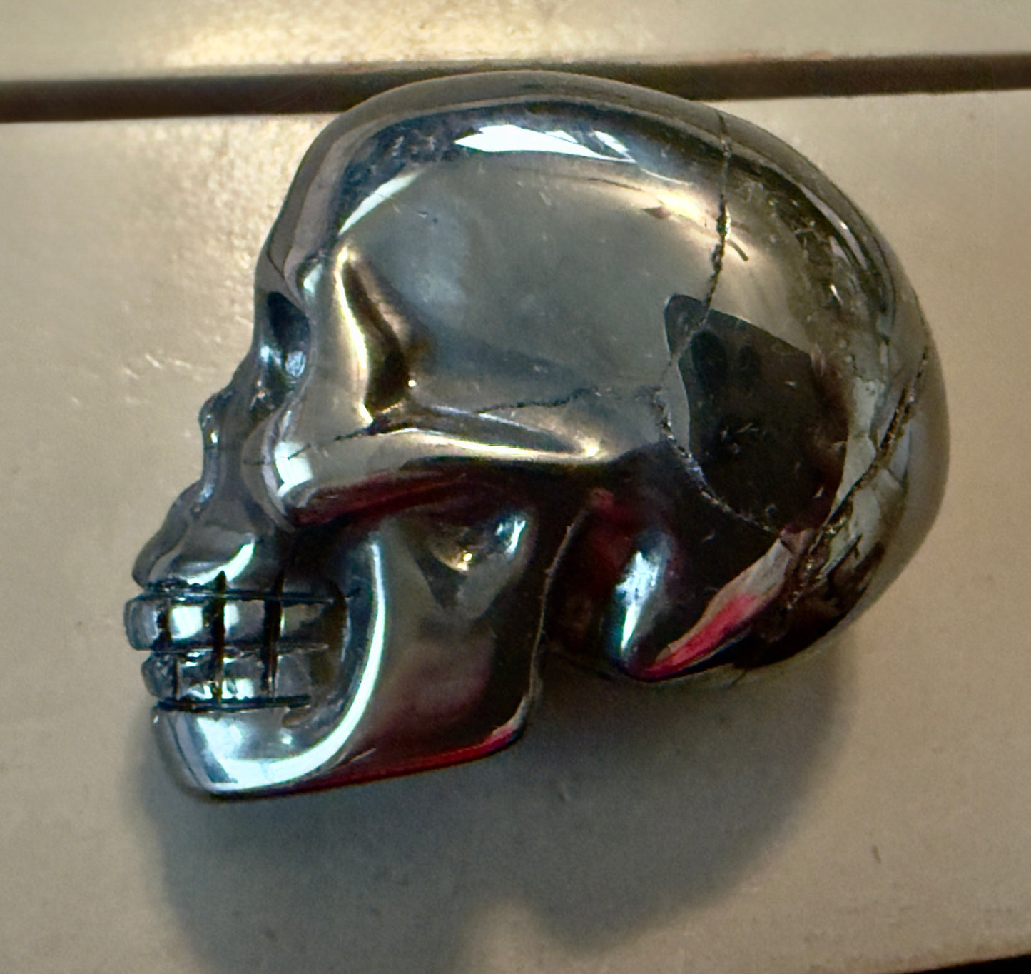 side view of silver hematite hand carved skull  fractures polished and unpolished natural 