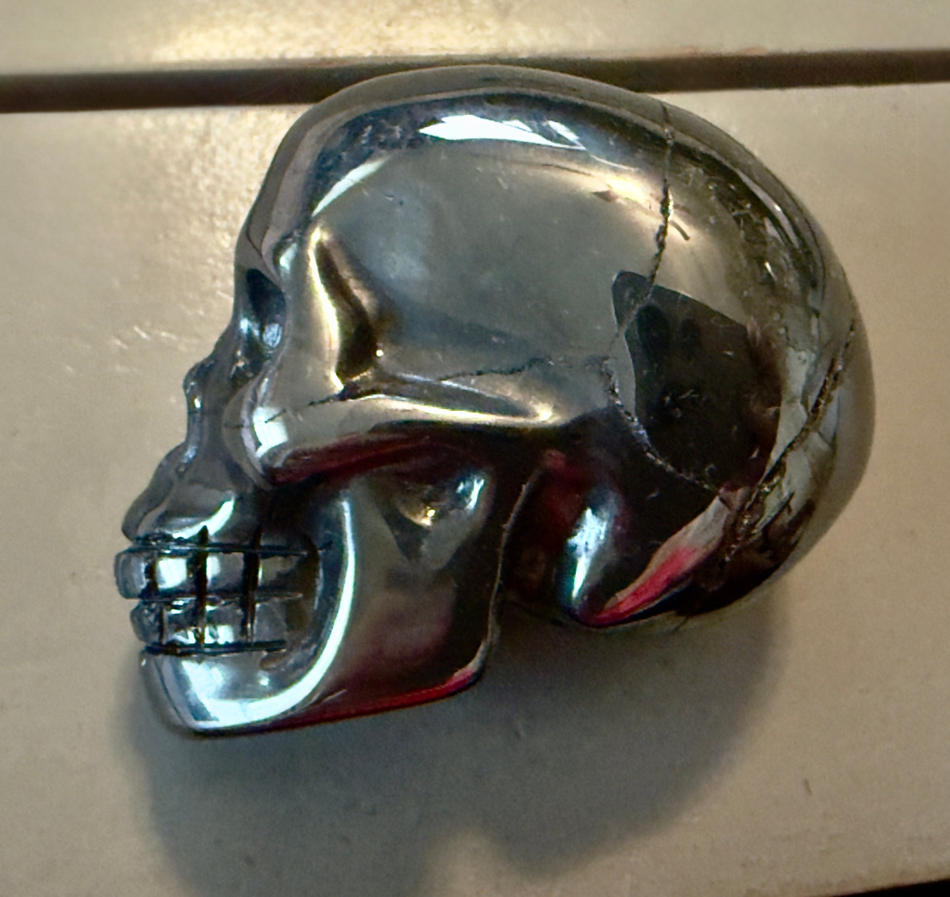 side view of silver hematite hand carved skull  fractures polished and unpolished natural 