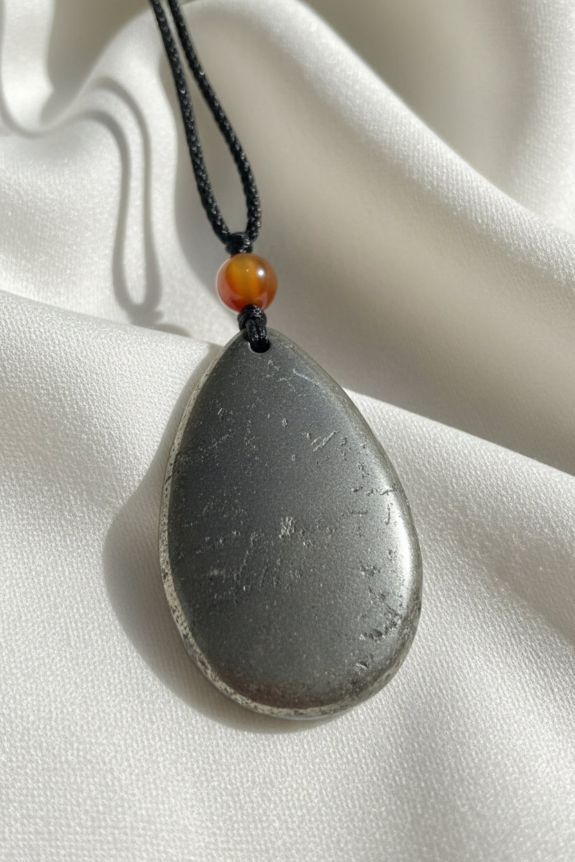 A teardrop-shaped hematite pendant adjustable cord and carnelian 8mm bead