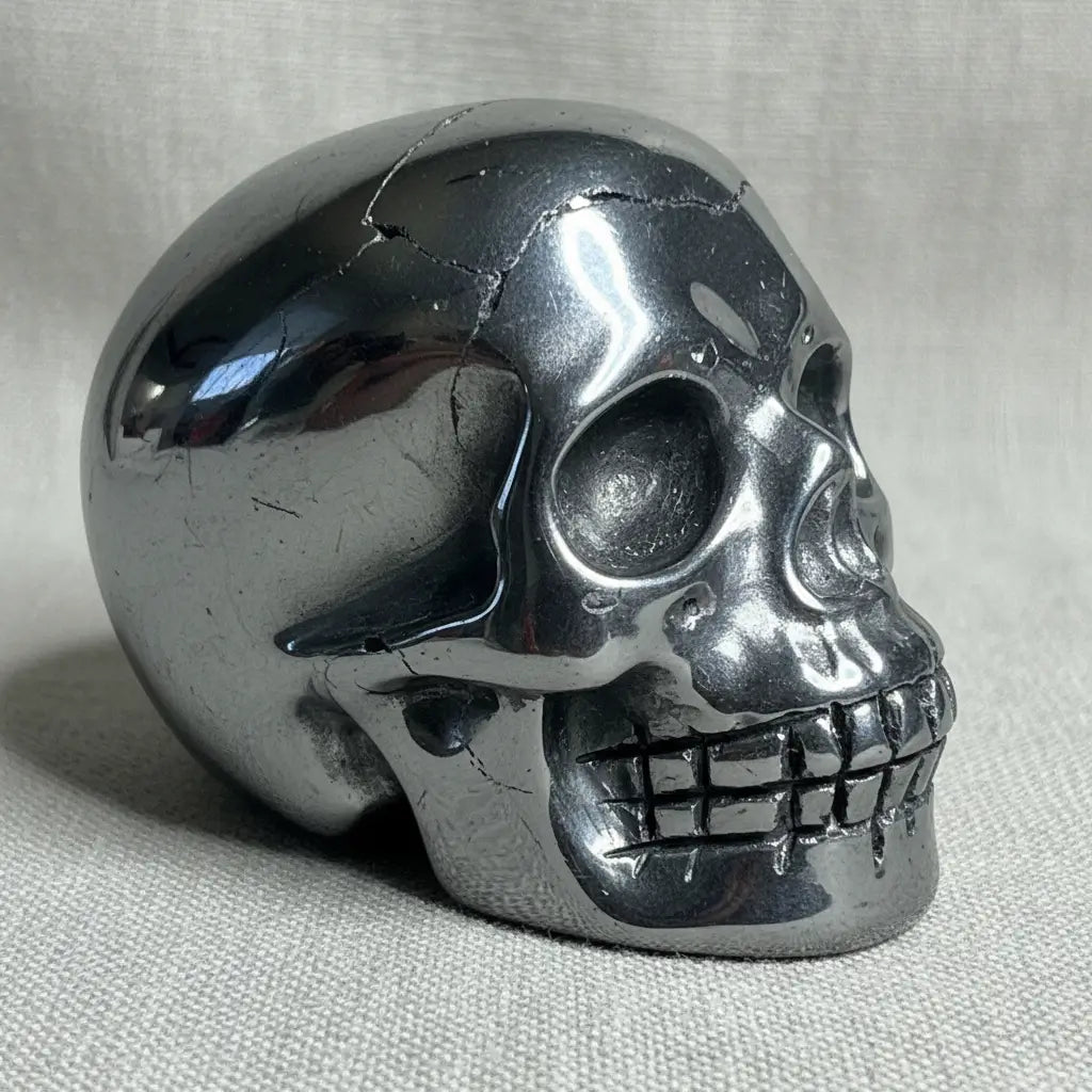close up side view of hematite hand carved skull polished silver with parts 