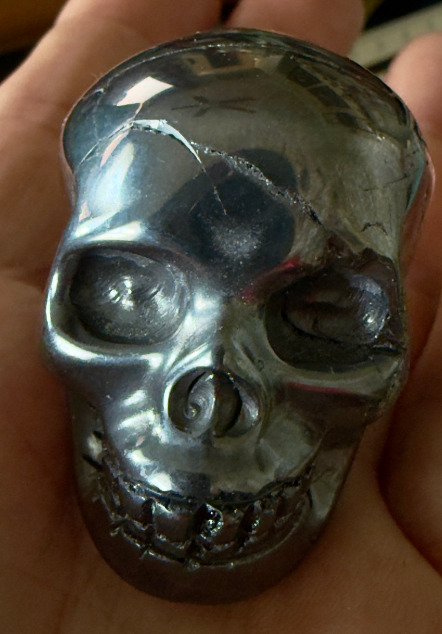 close up of the front of a hematite hand carved human skull polished silver 