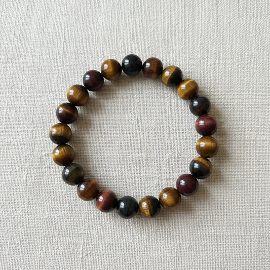 rainbow tigers eye crystal bracelet laying on a white rock 