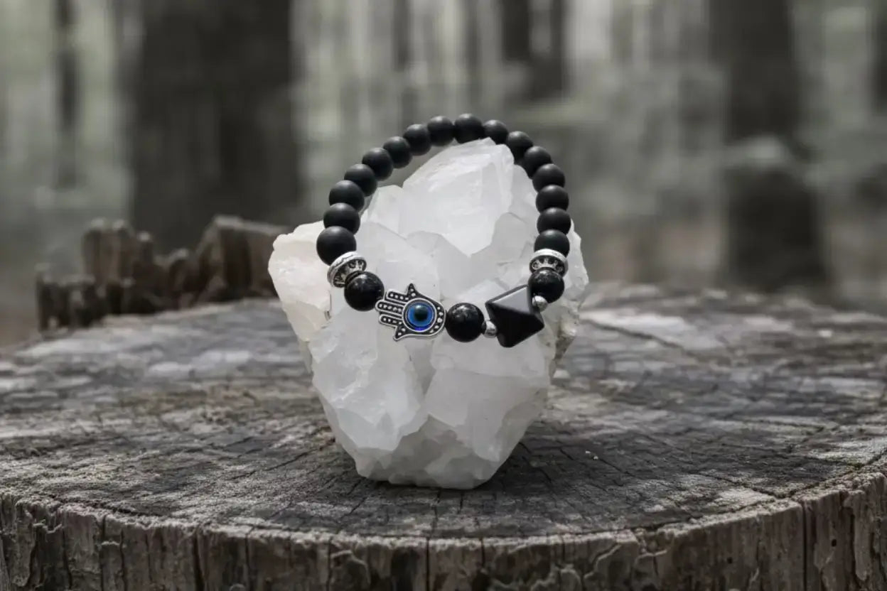 Black Obsidian Bracelet with Black Obsidian pyramid charm and Hamsa Charm on a tree stump in the forest