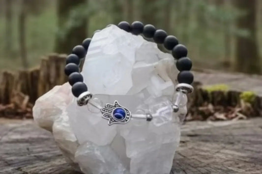 black obsidian bracelet on a white rock displayed on a tree stump in the forest