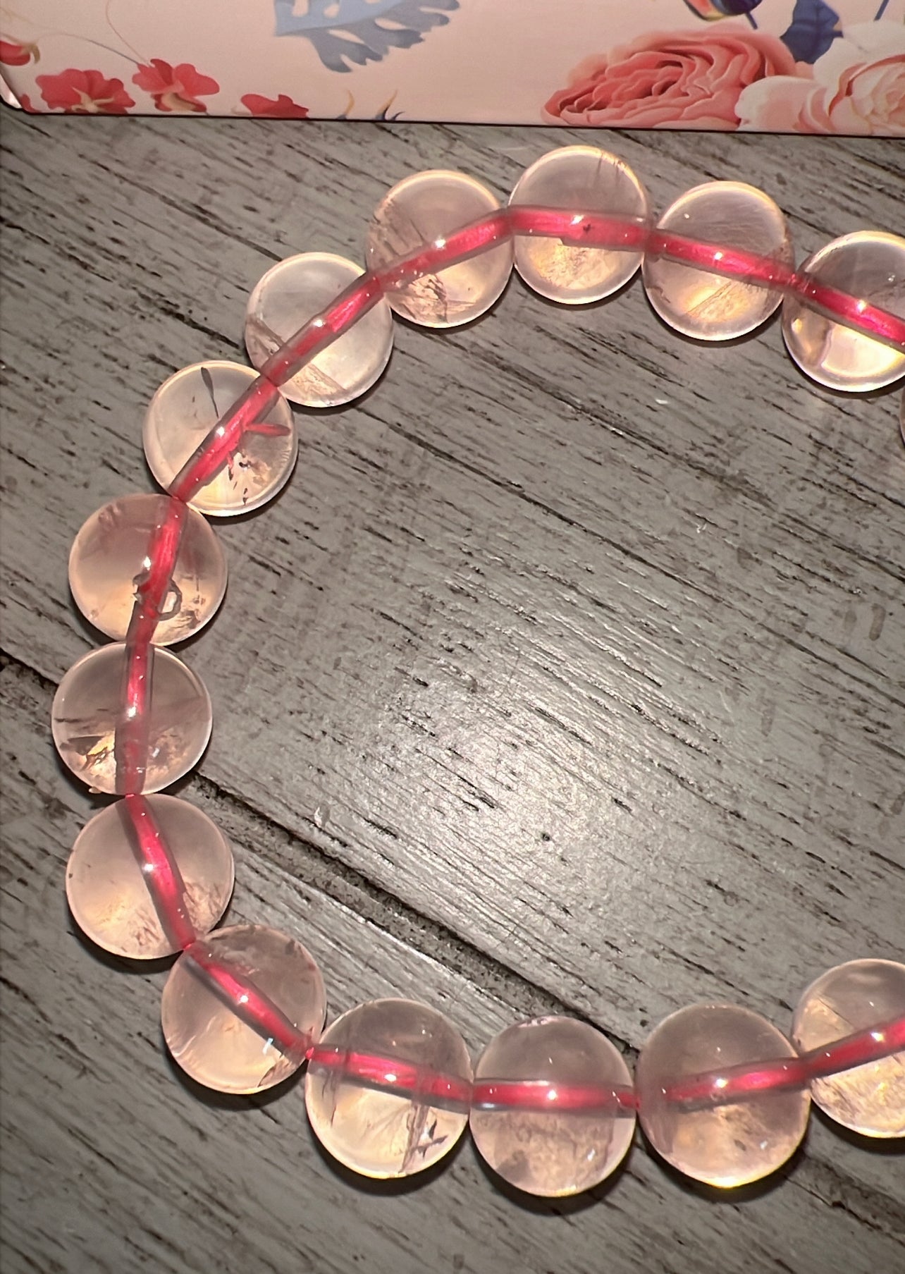 Rose quartz crystal bracelet on wooden surface.
