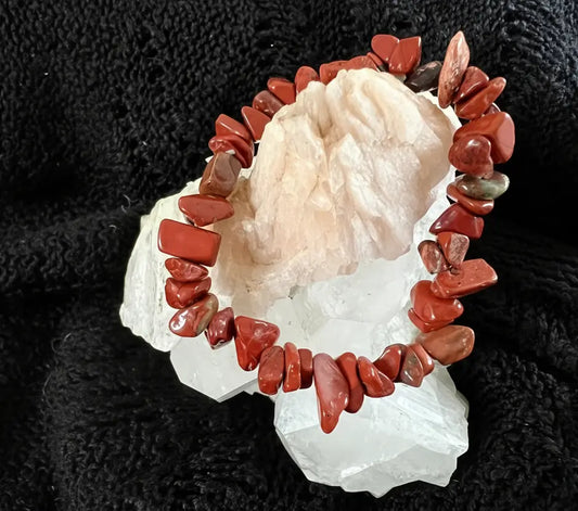 Red Jasper Crystal Chip Bracelet displayed on a white rock