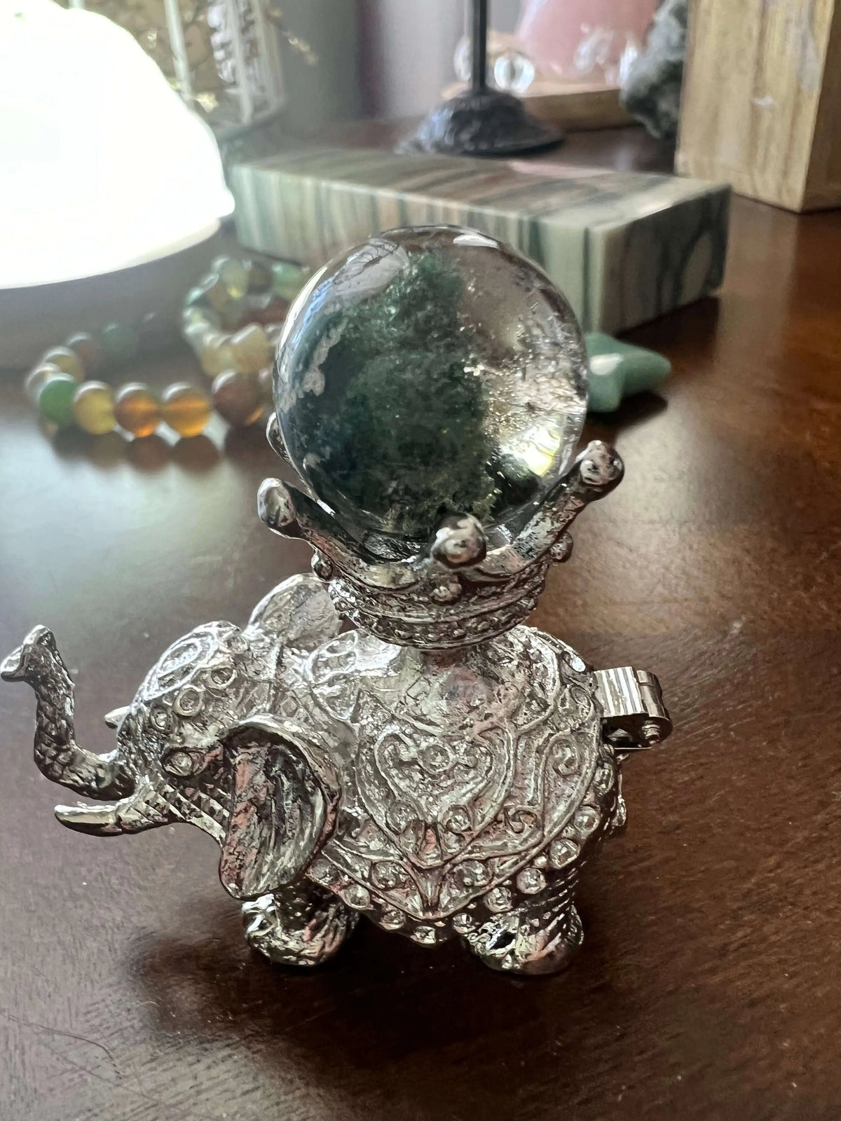 Silver elephant figurine holding a crystal ball.