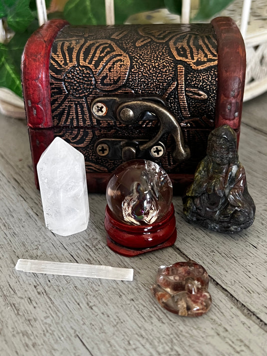 Close-up of crystals and a treasure chest on a gray wood surface.