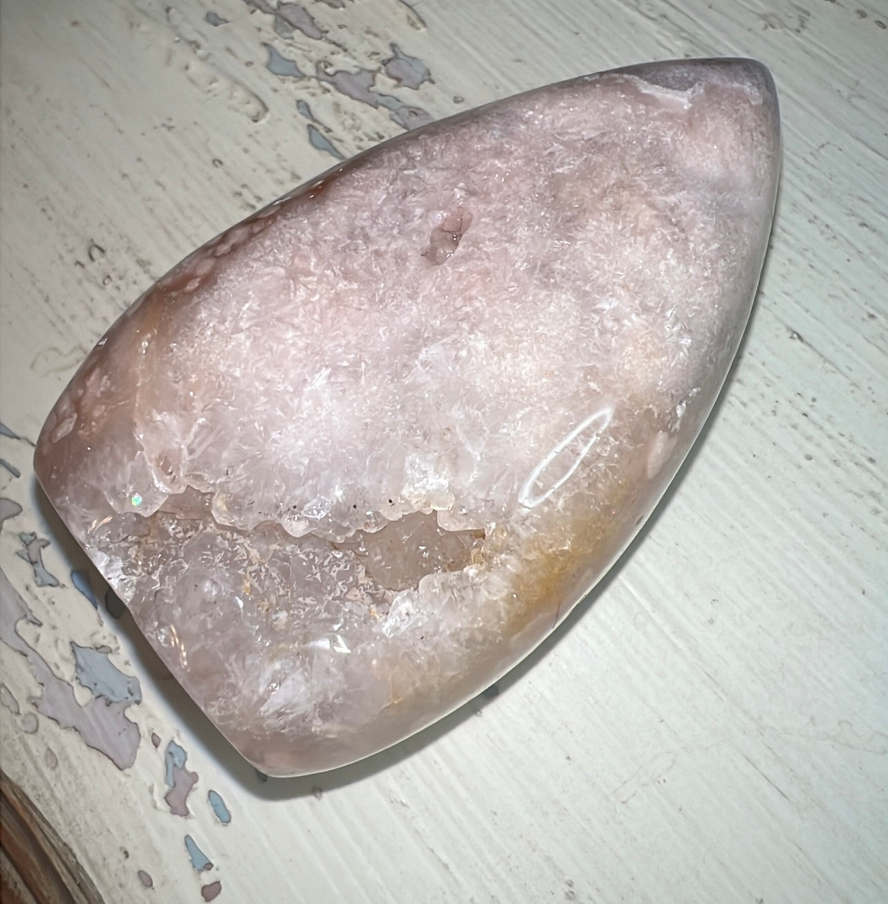 Polished geode with a crystalline center on a weathered white surface.