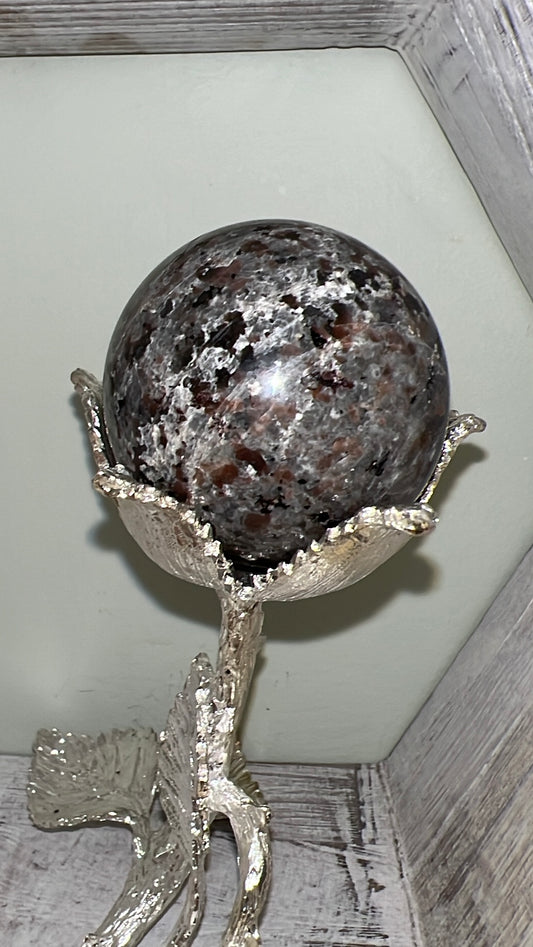 Sphere with brown and gray pattern in silver floral stand.
