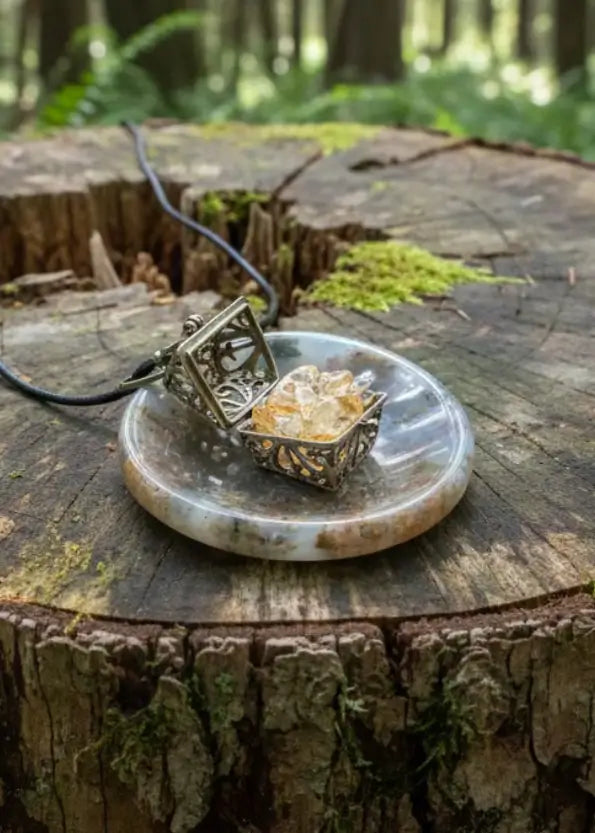Open gold locket with citrine crystals on round agate pendant with black cord.
