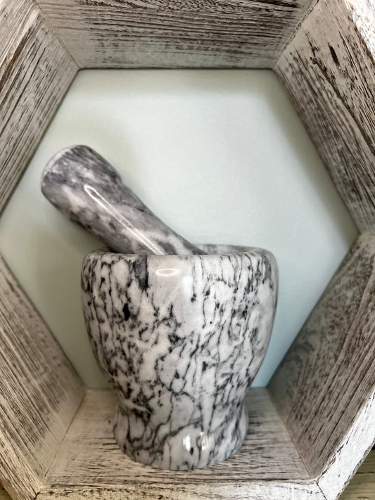 Marble mortar and pestle in a white wooden hexagon shelf.