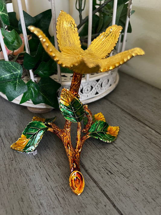 Close-up of a golden flower-shaped candle holder with green leaves, set against a white birdcage.  Flower Sphere Display Stand 