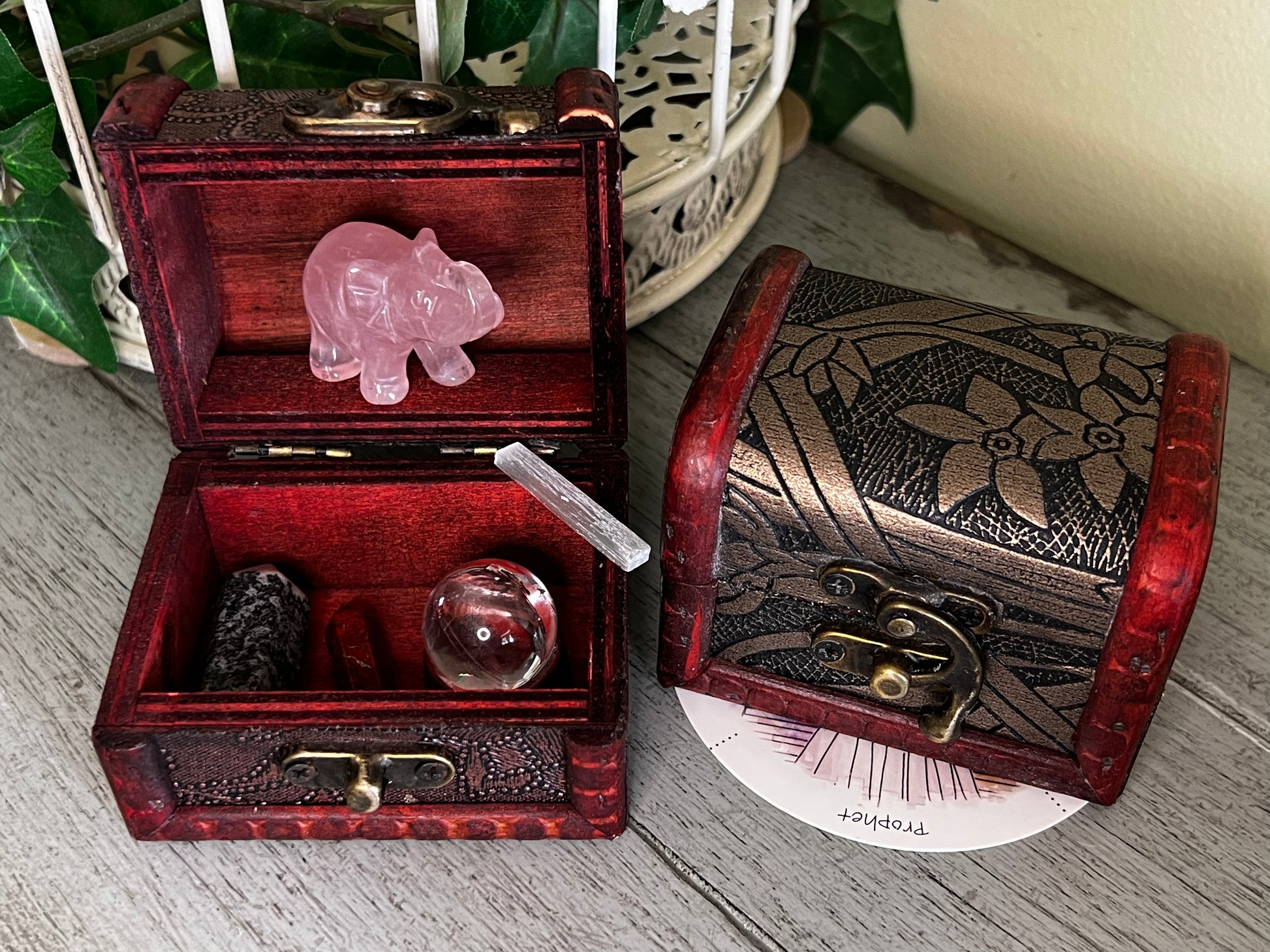 Two open wooden treasure chests with crystals, including a rose quartz elephant.
