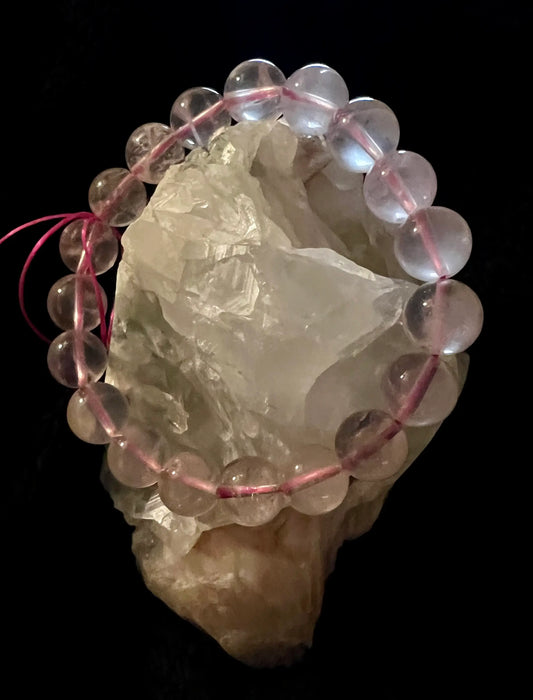Pink beaded bracelet on a large clear crystal stone against a black background.
