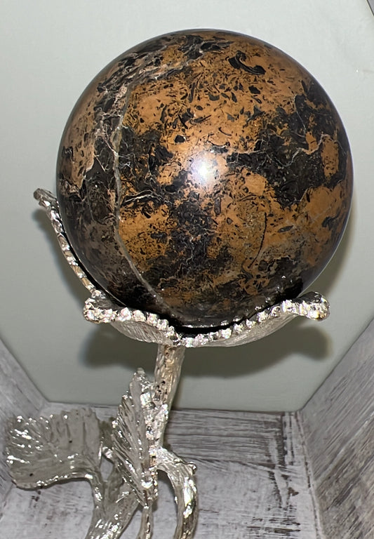 A brown and black stone sphere on a silver stand.
