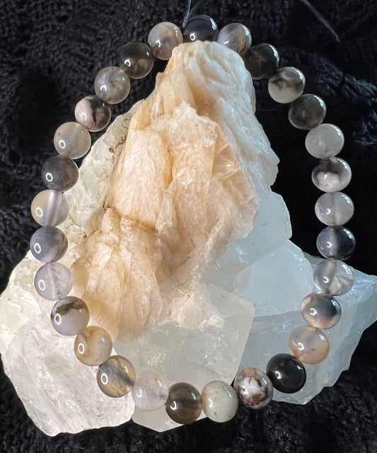 A beaded bracelet encircles a cluster of light-colored crystals.