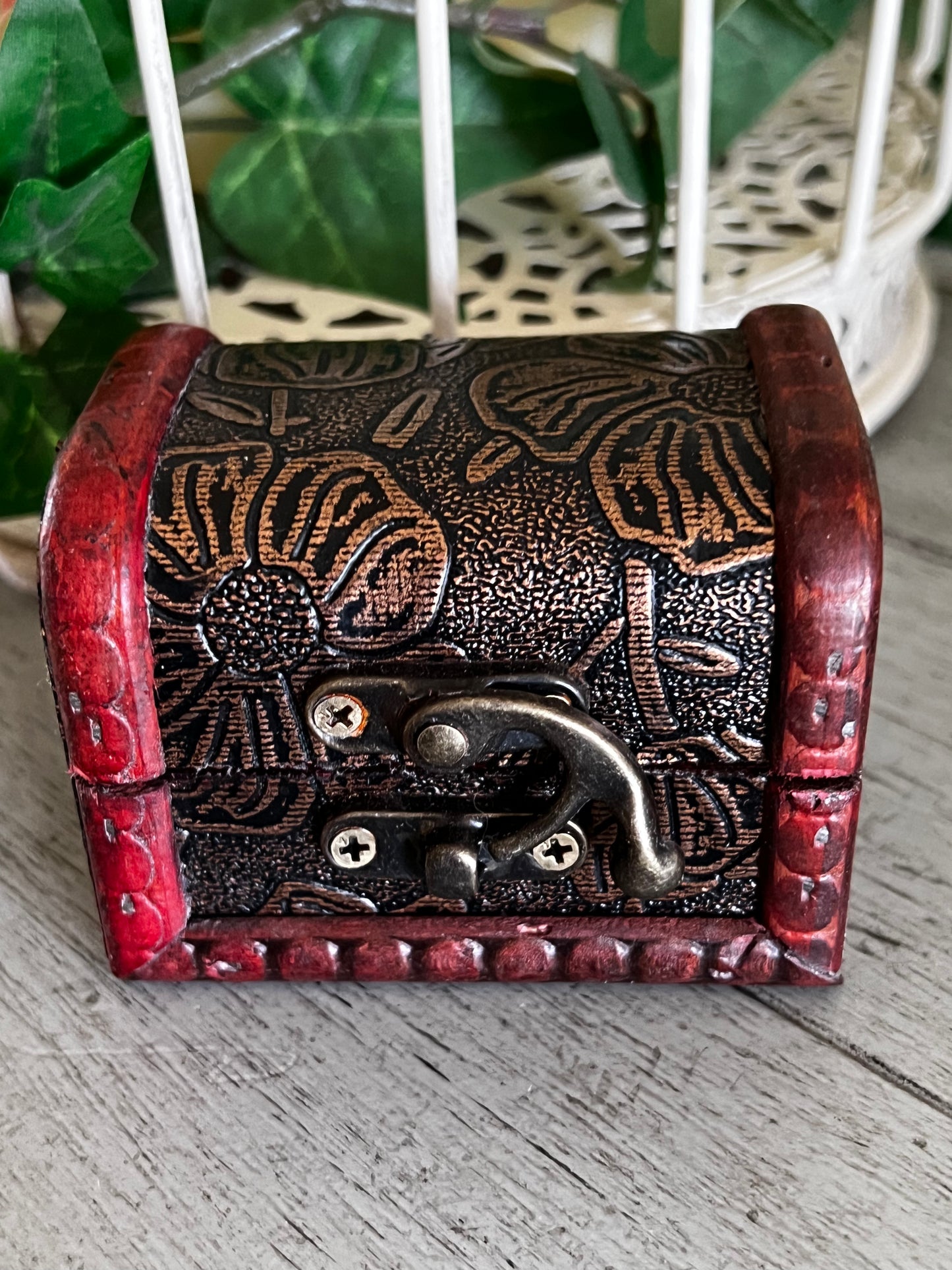 Small wooden chest with red trim and floral design.
