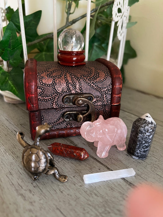 Small wooden chest with crystals and metal turtle figurine.