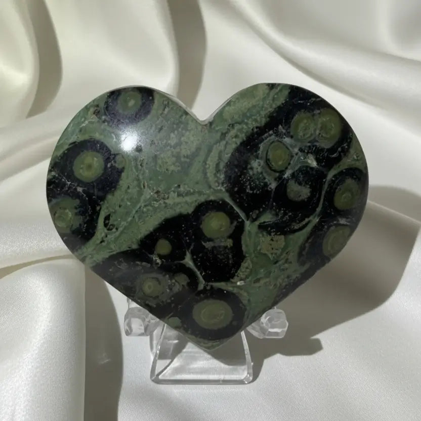 close up of a kambaba jasper carved heart bright green and dark green hues with black swirls through out 