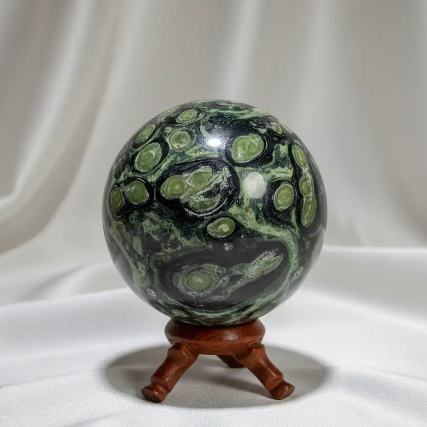 up close image of kambaba jasper sphere green hues dark to light green with kambaba back swirls 