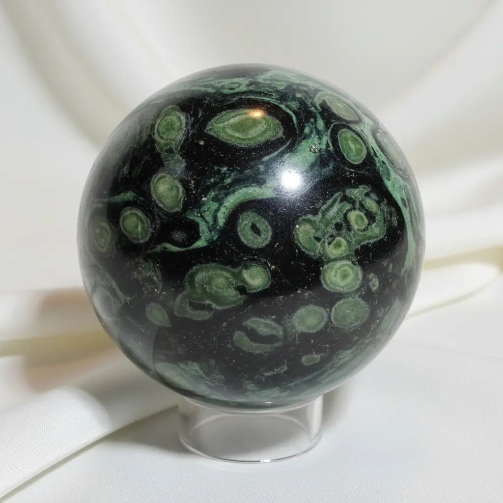 Close -up of kambaba jasper sphere kambaba has green hues from dark to lime green with black swirls through out 