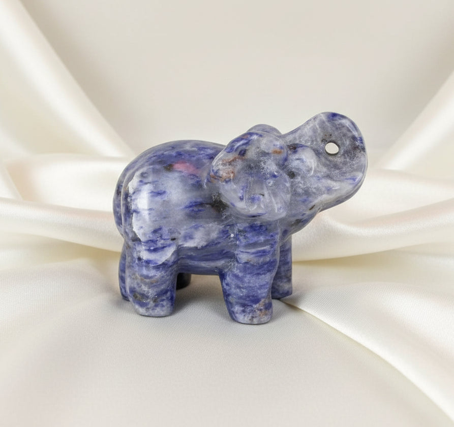 A carved elephant figurine made of polished lapis lazuli photographed on a light surface  