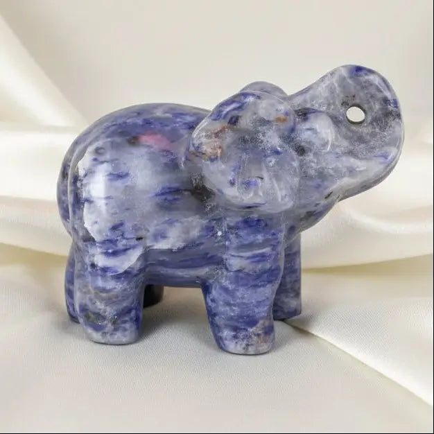 A carved elephant figurine made of polished lapis lazuli photographed on a light surface  