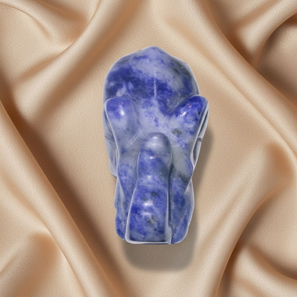 looking down at a lapis lazuli crystal elephant figurine, photographed from a top-down angle on a white surface 