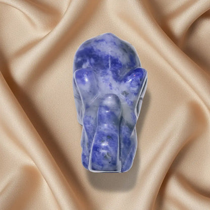looking down at a lapis lazuli crystal elephant figurine, photographed from a top-down angle on a white surface 