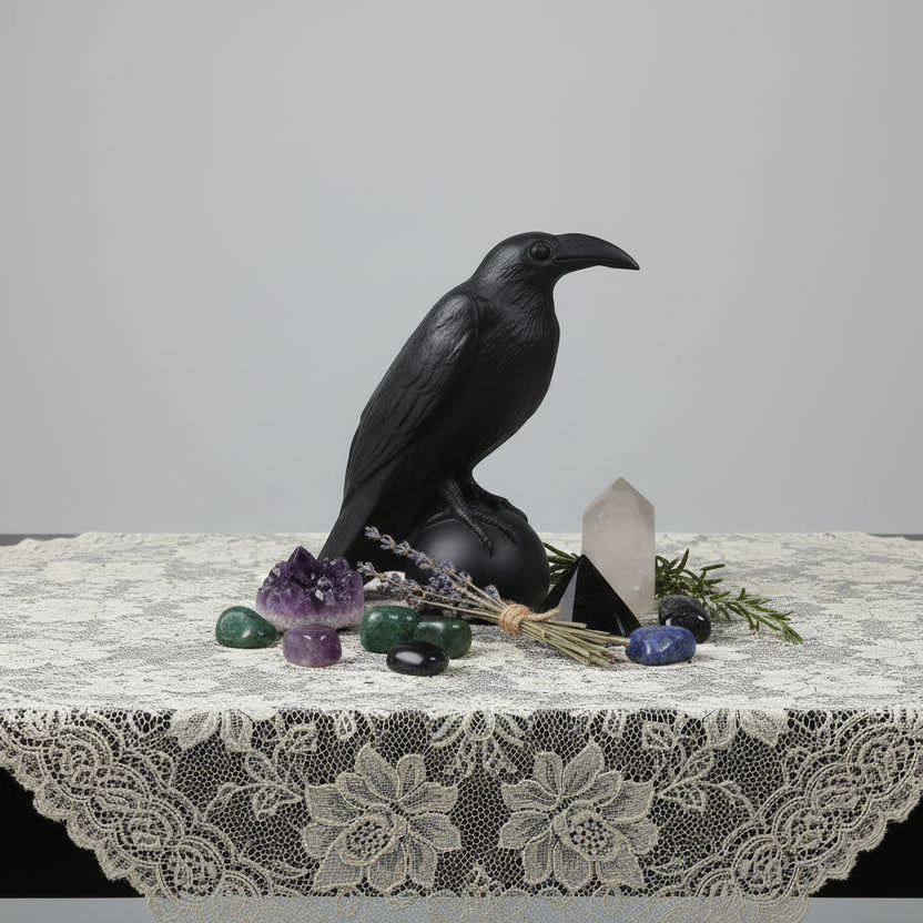 beautiful black obsidian raven carving on a table lace cloth with clear quartz, herbs and tumbles all around