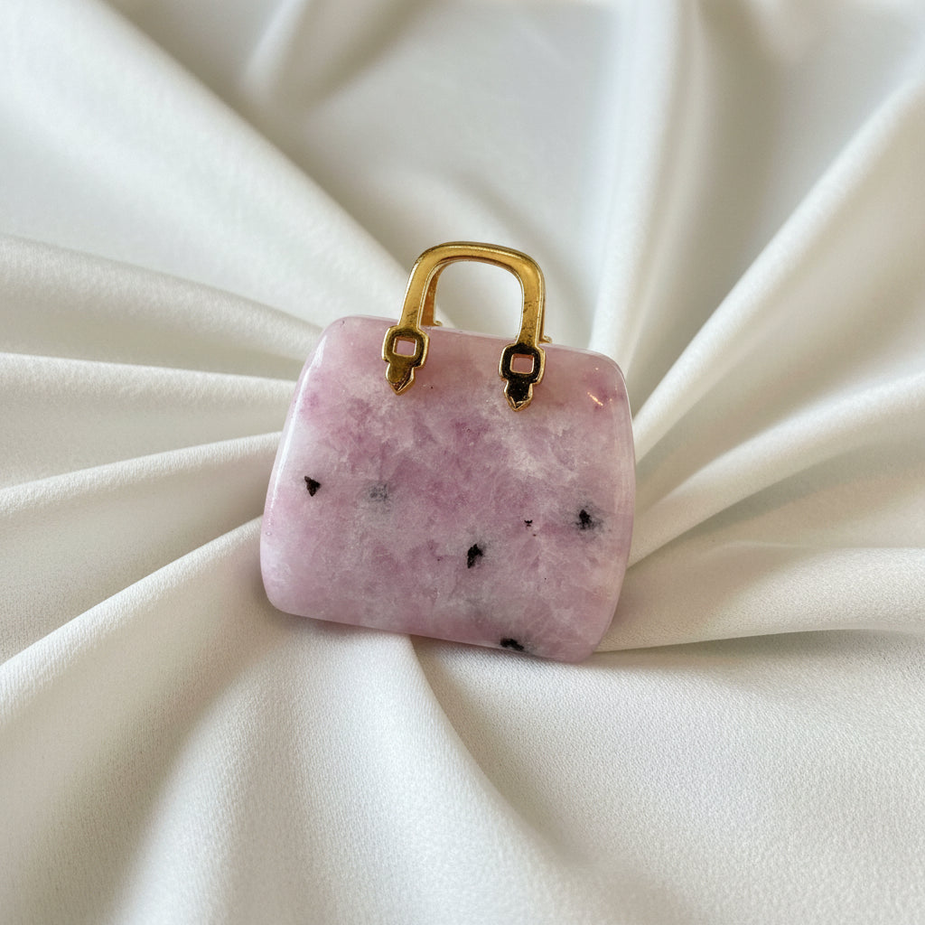 close-up of lepidolite carved handbag with a gold tone handle pinks and black crystal