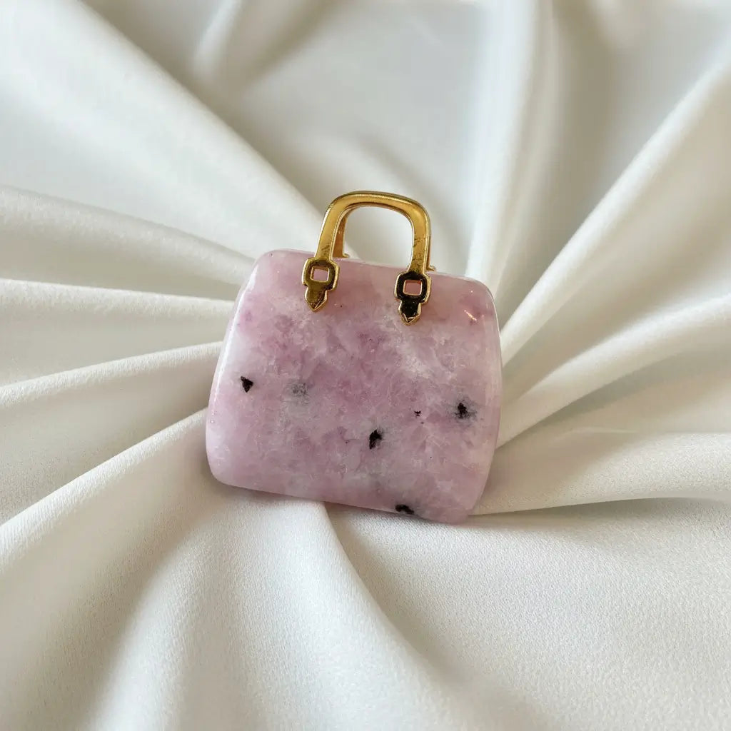 close-up of lepidolite carved handbag with a gold tone handle pinks and black crystal