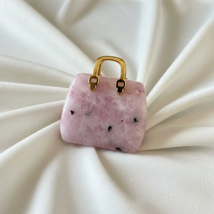 close-up of lepidolite carved handbag with a gold tone handle pinks and black crystal