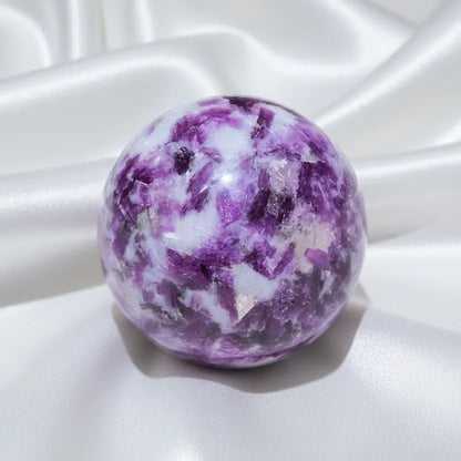 A polished lepidolite crystal sphere with a marbled pattern of purple, white, and pinkish tones