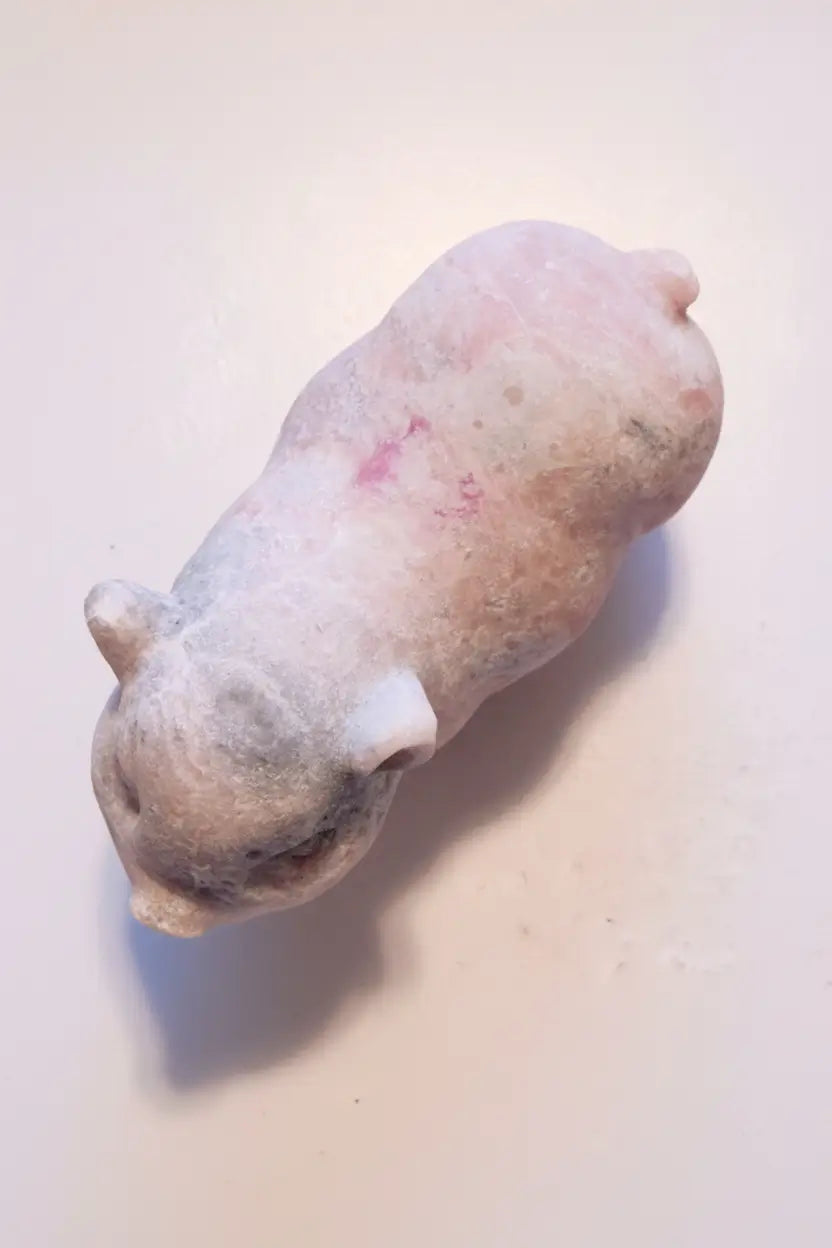 over head photo of pink calcite carved pig  colors are pink and gray